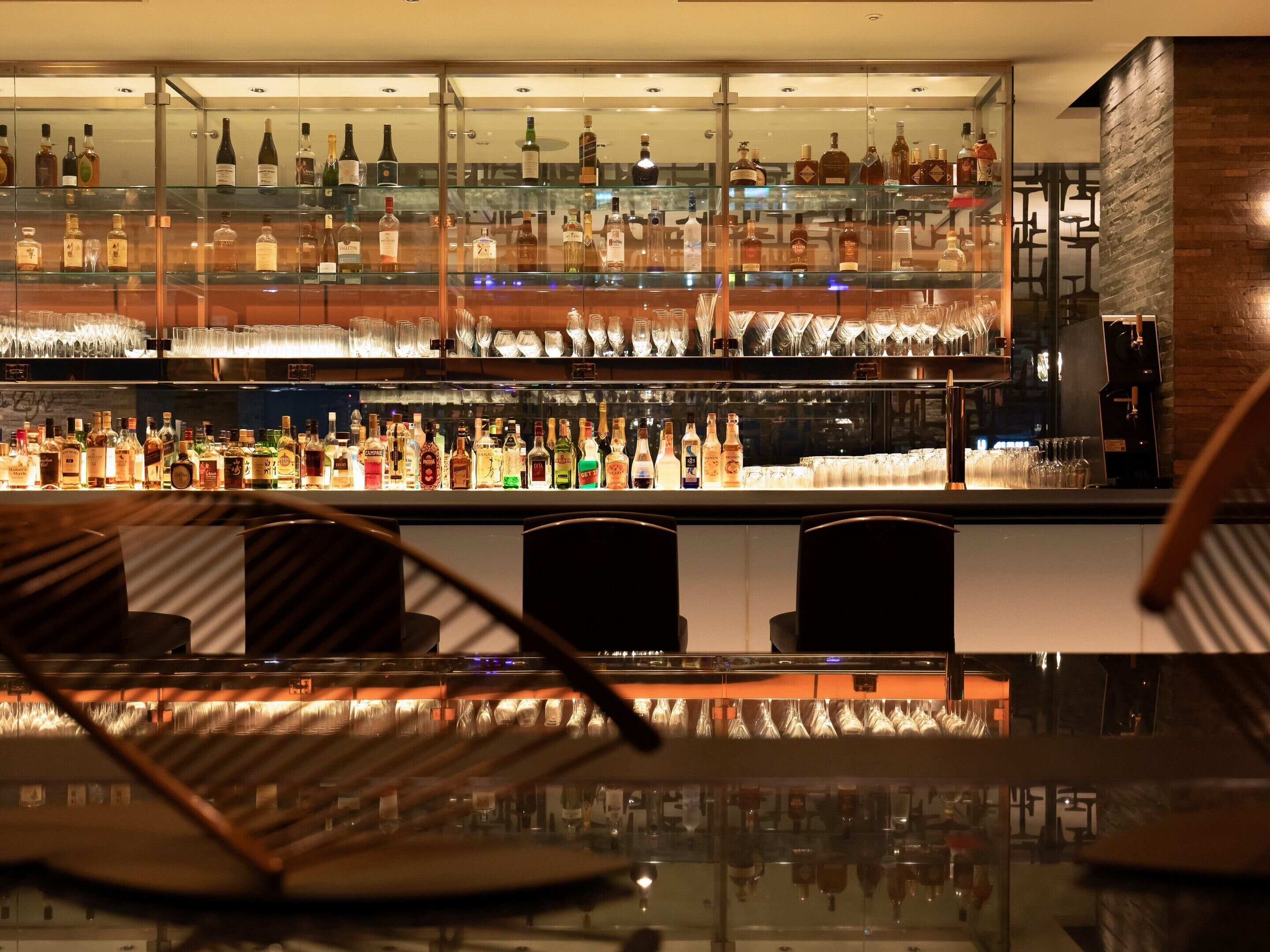 A bar area with multiple shelves of liquor bottles and glasses.