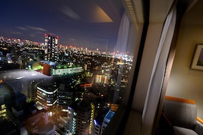 A high-rise hotel room with a city view, large windows, and a modern interior design.