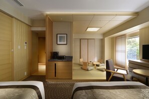 A hotel room with two beds, a small kitchenette, a sitting area with a tatami mat, and a large window offering a view of greenery. - Hotel Metropolitan Tokyo Ikebukuro (Tokyo)