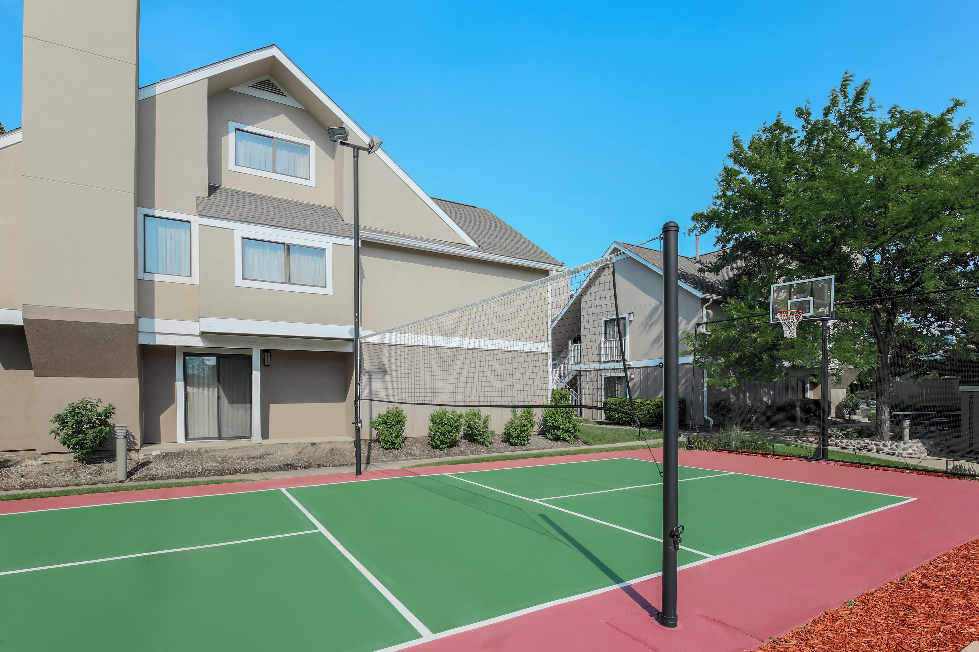 A multi-story residential building with a tennis court in front.