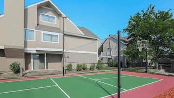 A multi-story residential building with a tennis court in front.