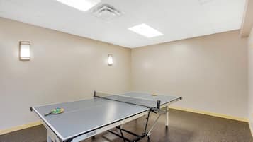 A ping pong table in a room with two wall-mounted lights and a ceiling light fixture.