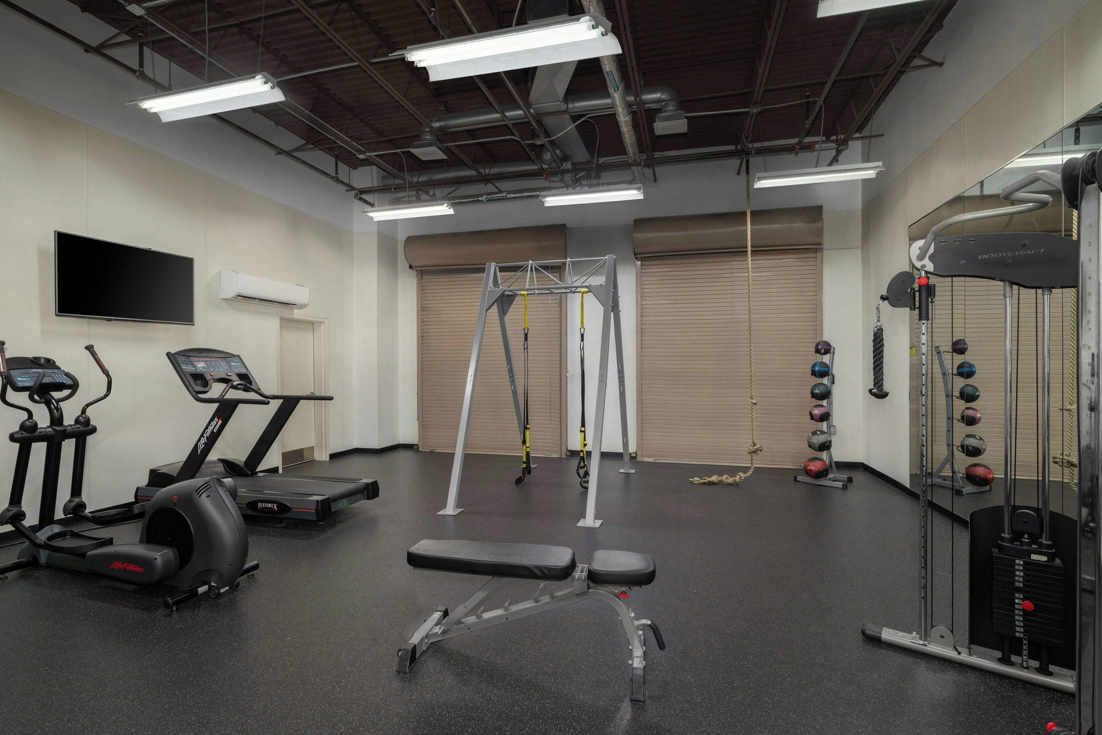 A gym with treadmills, a stationary bike, a weight bench, and a cable machine.