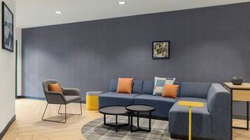 A modern living room with a grey sofa, a grey armchair, a round coffee table, and a yellow floor lamp.