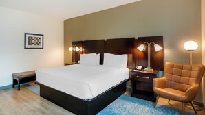 A hotel room with a large bed, bedside tables, a chair, and wall-mounted lamps. - City Express By Marriott King of Prussia (King of Prussia)