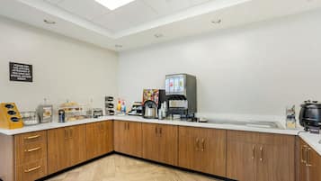 A modern kitchen with wooden cabinets, a coffee station, and a sign instructing to ask the kitchen staff about dietary needs.