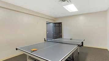 A room with two ping pong tables, a door, and a ceiling light.