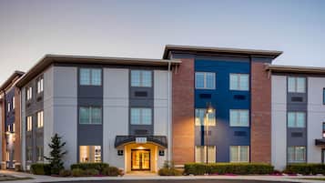 Un hotel Marriott Bonvoy de varios pisos con un diseño arquitectónico moderno, que combina fachadas de ladrillo y vidrio, y un exterior bien cuidado con jardines ajardinados.