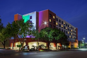 Un hotel DoubleTree by Hilton con diseño moderno, que destaca un letrero grande, varios pisos y una entrada bien iluminada.