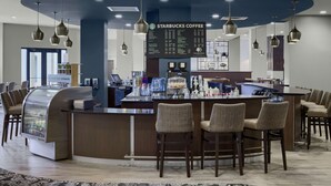 Una cafetería Starbucks con un mostrador curvo, taburetes de bar y un panel de menú.