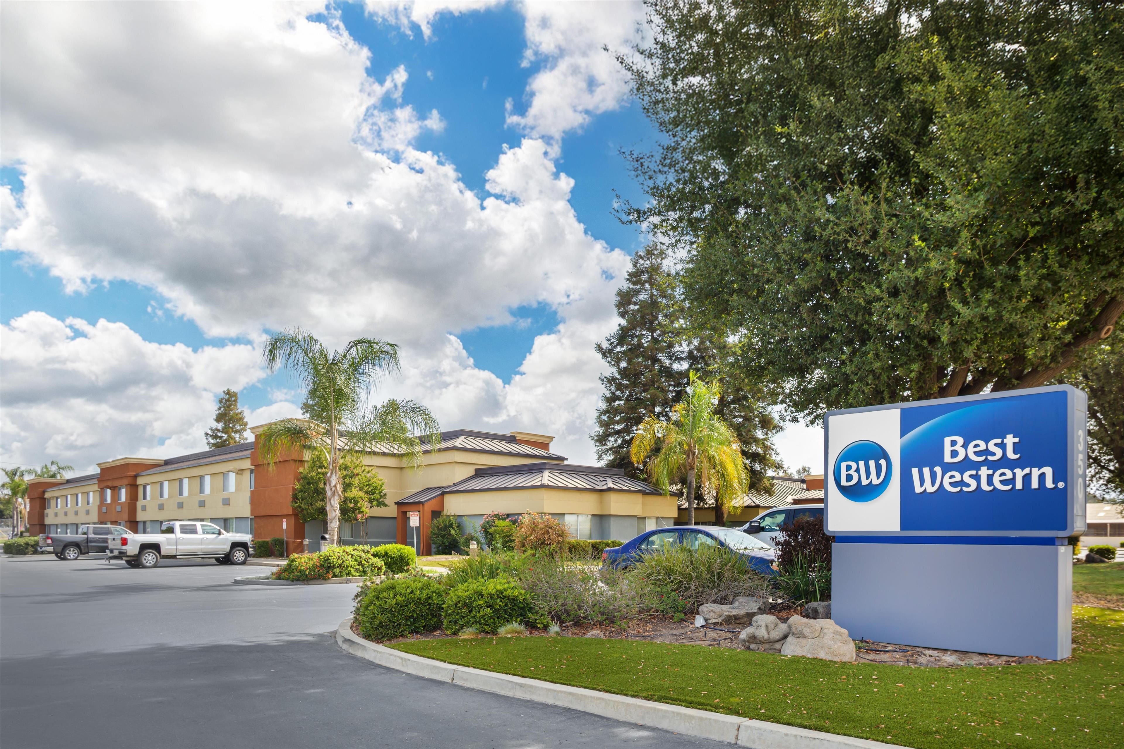 A Best Western hotel sign, a parking lot, and a building with multiple stories and a flat roof.