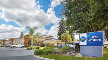 A Best Western hotel sign, a parking lot, and a building with multiple stories and a flat roof.