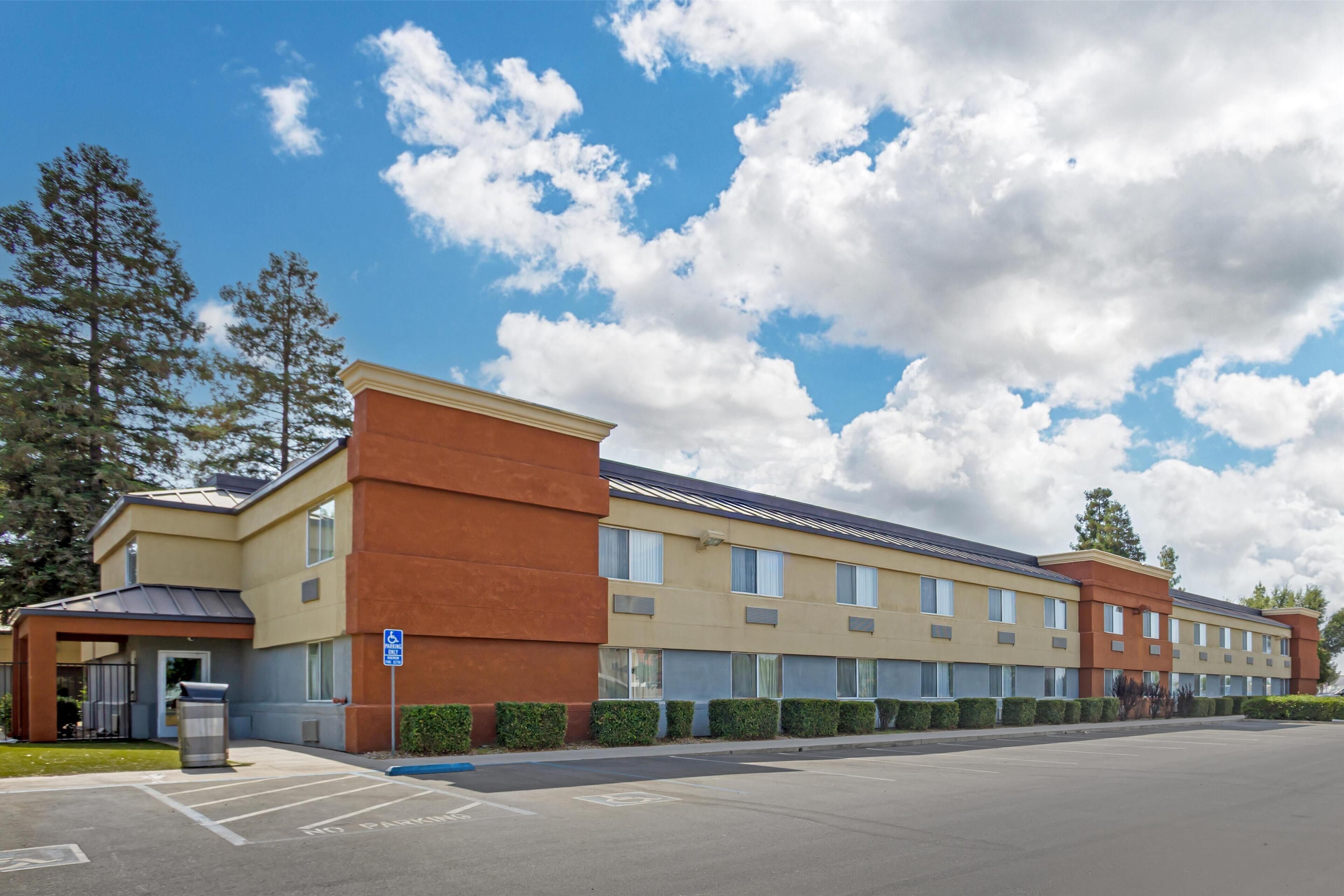 A multi-story hotel with a parking lot in front.