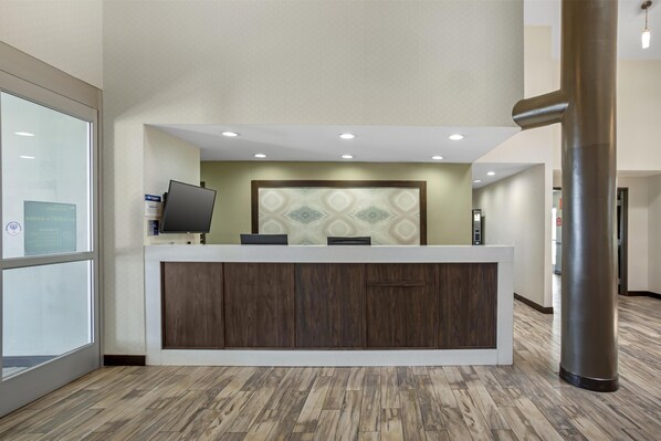 A reception desk with a modern design, a flat-screen TV, and a patterned wall behind it.