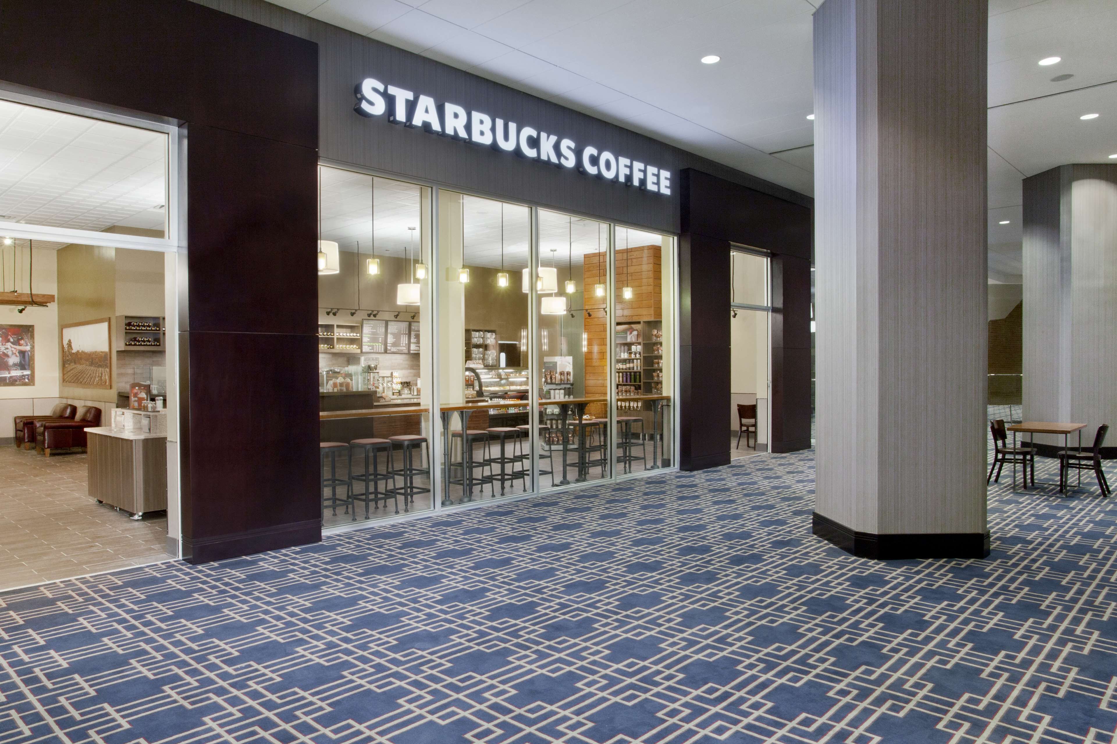 Un café Starbucks au décor moderne, avec un tapis à motifs et un espace salon comprenant des tables et des chaises.