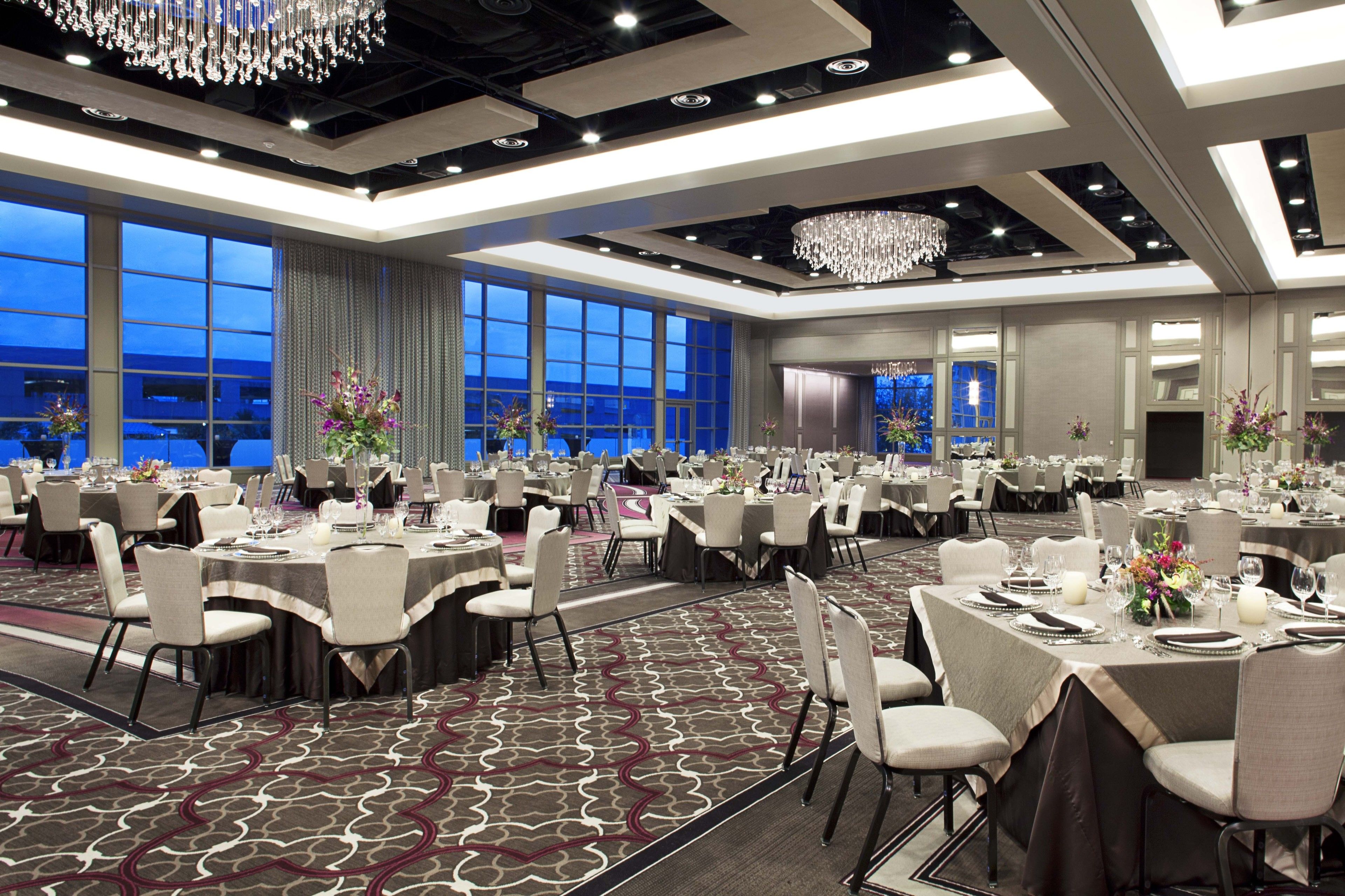 Un amplio salón de banquetes con mesas redondas, sillas y candelabros.
