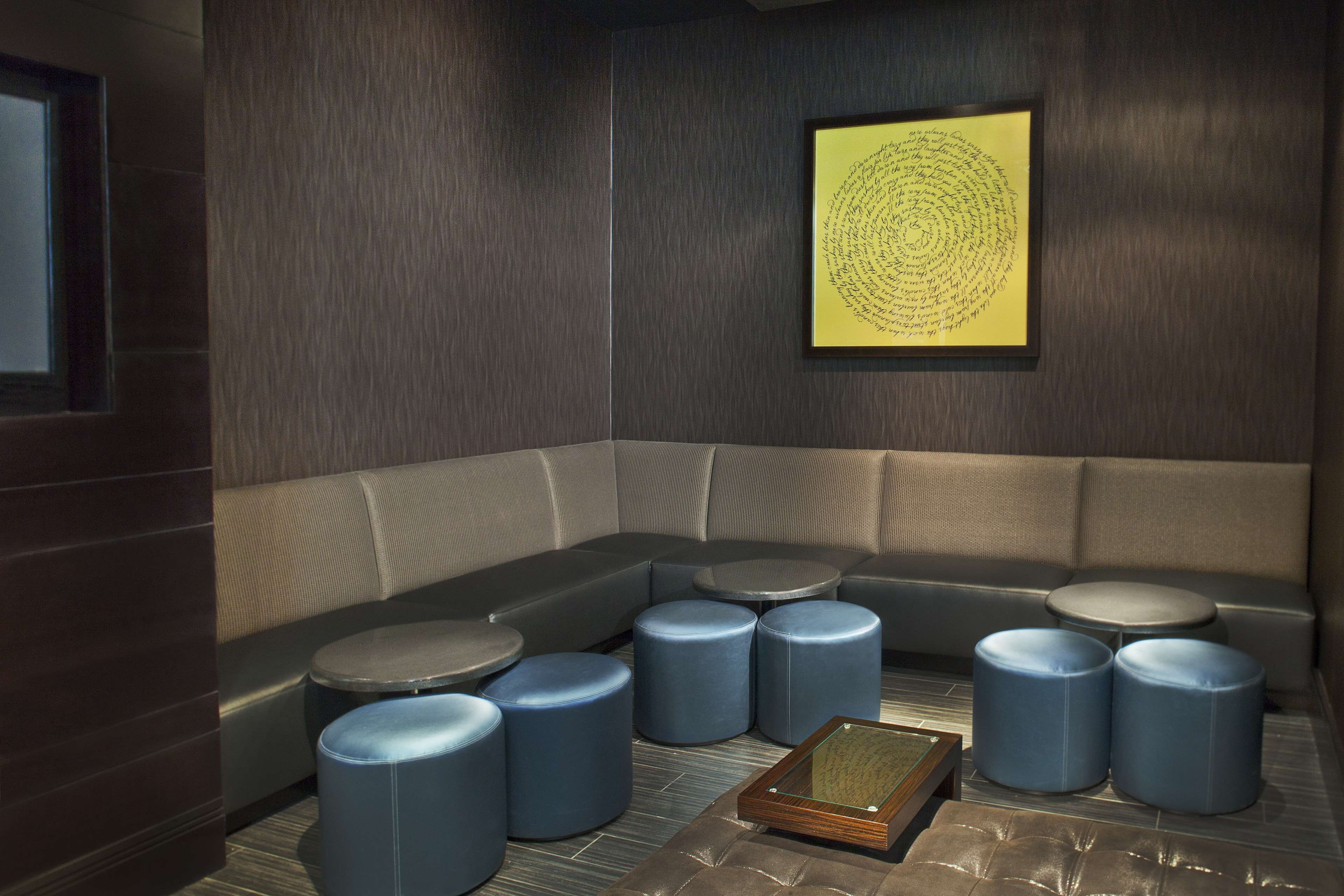 Ein moderner Lounge-Bereich mit einer gebogenen Couch, mehreren runden Tischen und blauen Hocker.
