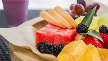 A wooden tray with various fruits including watermelon, strawberries, blackberries, and pineapple slices.
