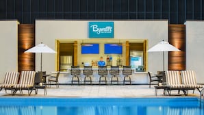A pool area with a bar named 'Bywater Pool Deck & Bar', featuring lounge chairs and umbrellas.