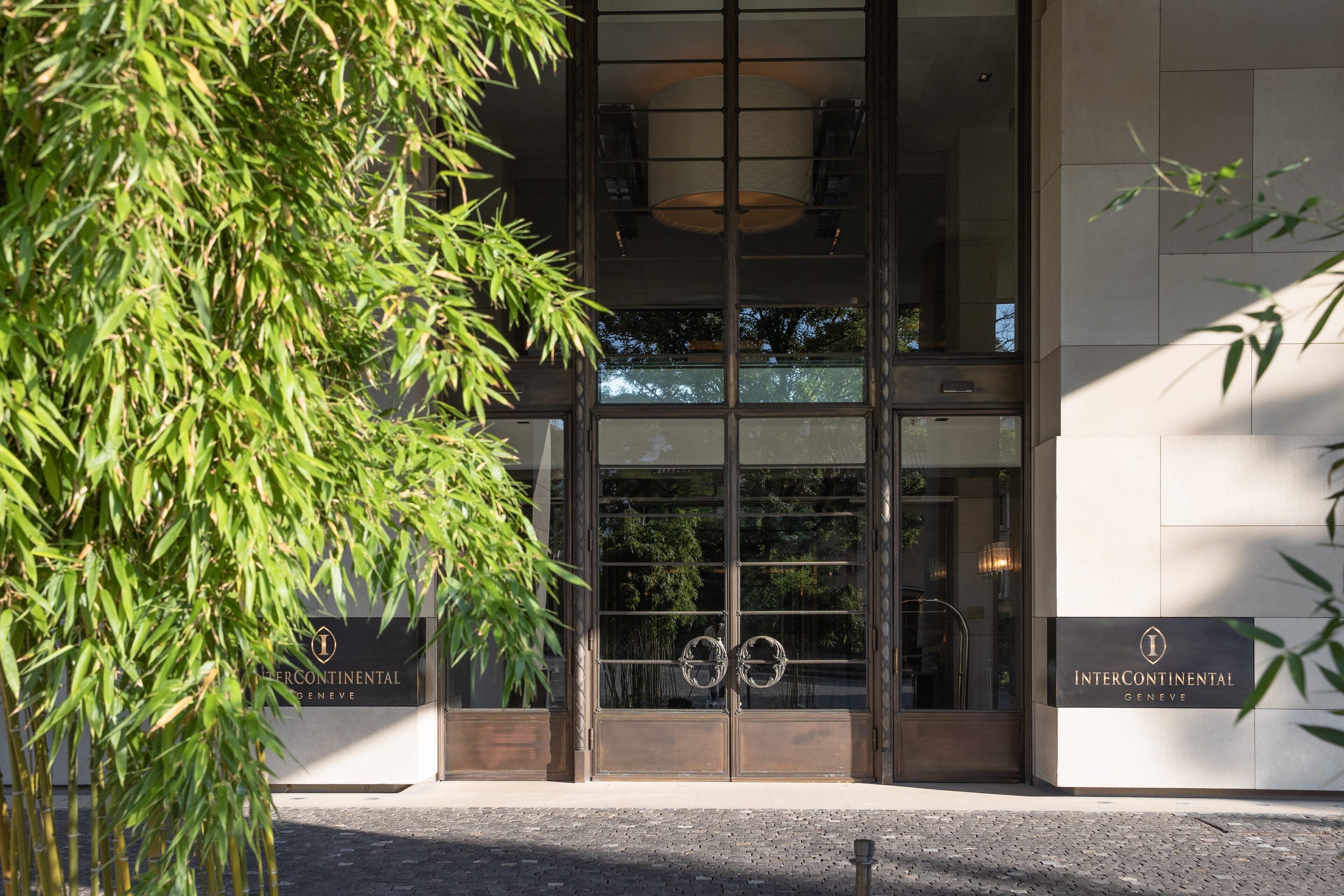 A building entrance with a glass facade, a metal gate, and a sign reading 'INTERCONTINENTAL GENEVE'.