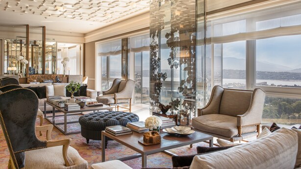 A spacious living room with a large window offering a city view, a fireplace, and a modern ceiling design.