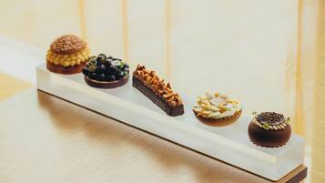 Un plateau rectangulaire blanc contenant cinq desserts différents, posé sur une surface en bois.