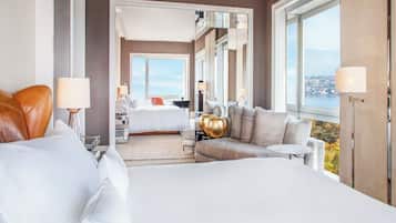 A hotel room with a large bed, a sofa, a desk, and a view of a body of water.