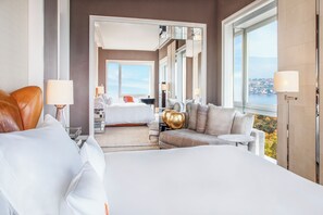 Habitación de hotel con una cama grande, un sofá, un escritorio y vistas a un cuerpo de agua.