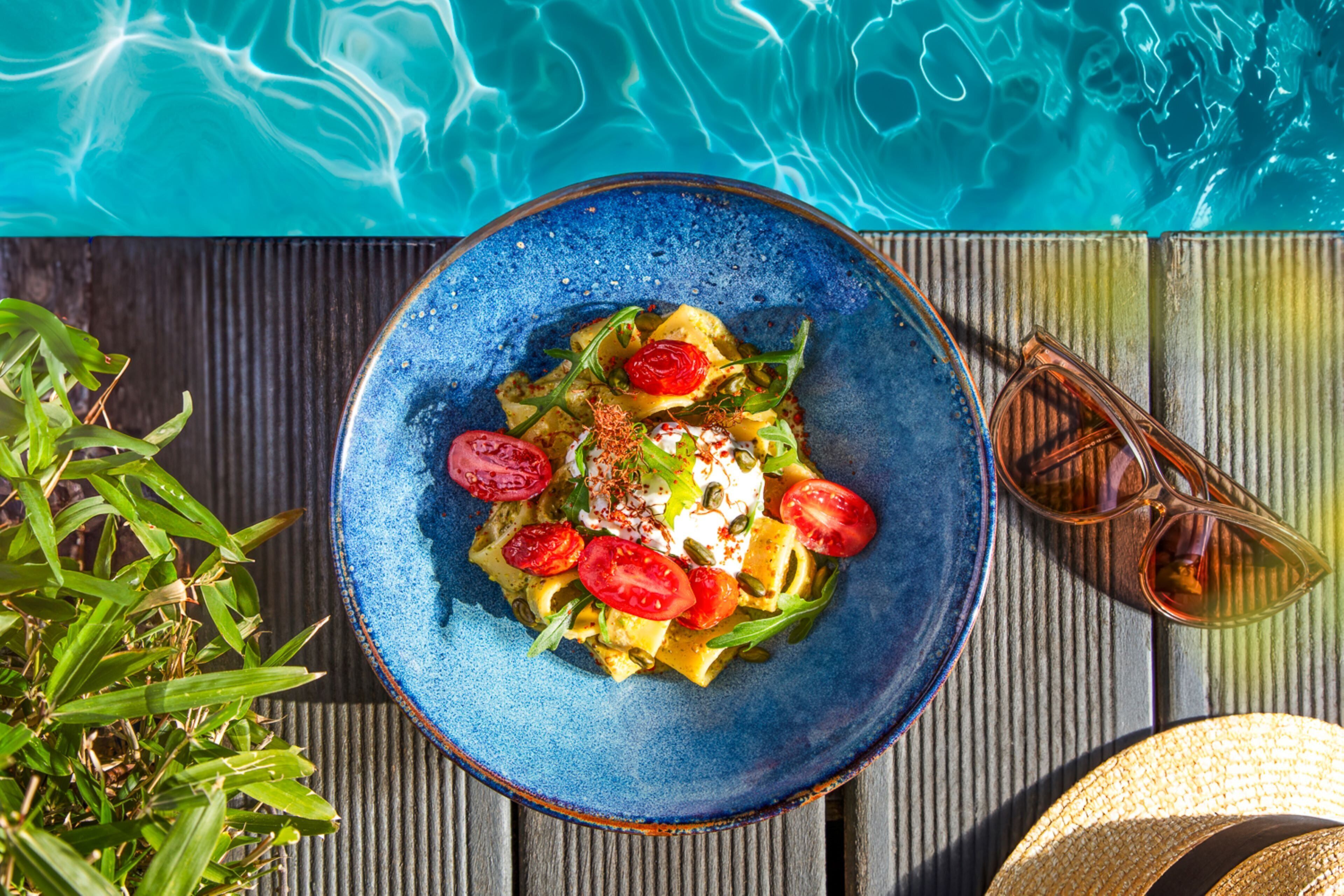 A bowl of food with tomatoes and a dollop of cream on a wooden surface.