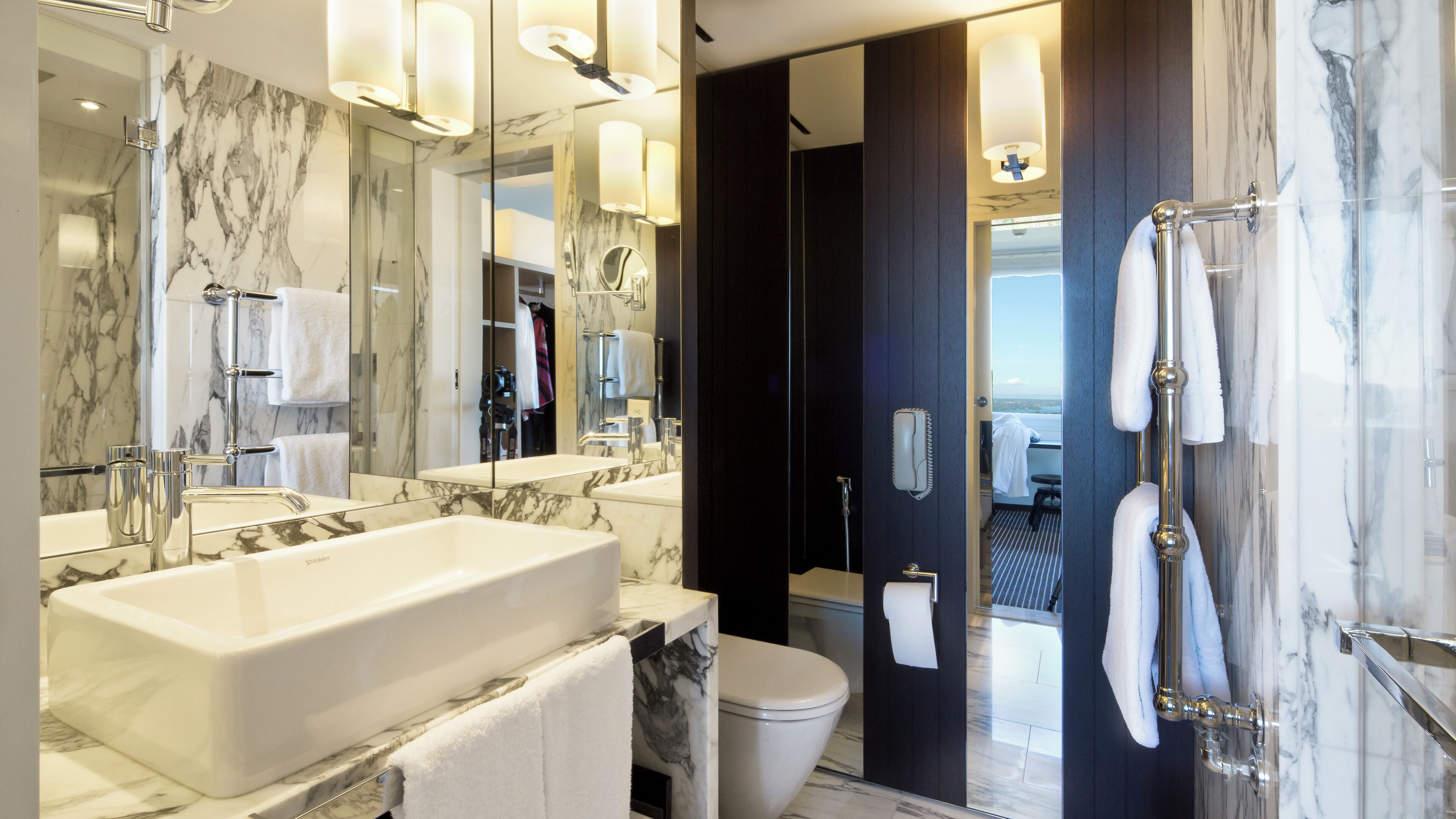 A modern bathroom with a large marble sink, a separate shower area, and a toilet.