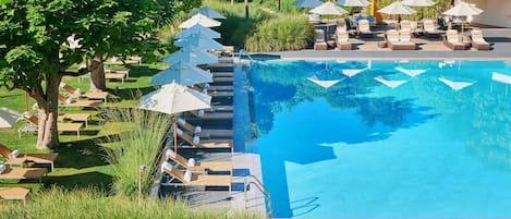 A pool area with lounge chairs and umbrellas, surrounded by greenery.