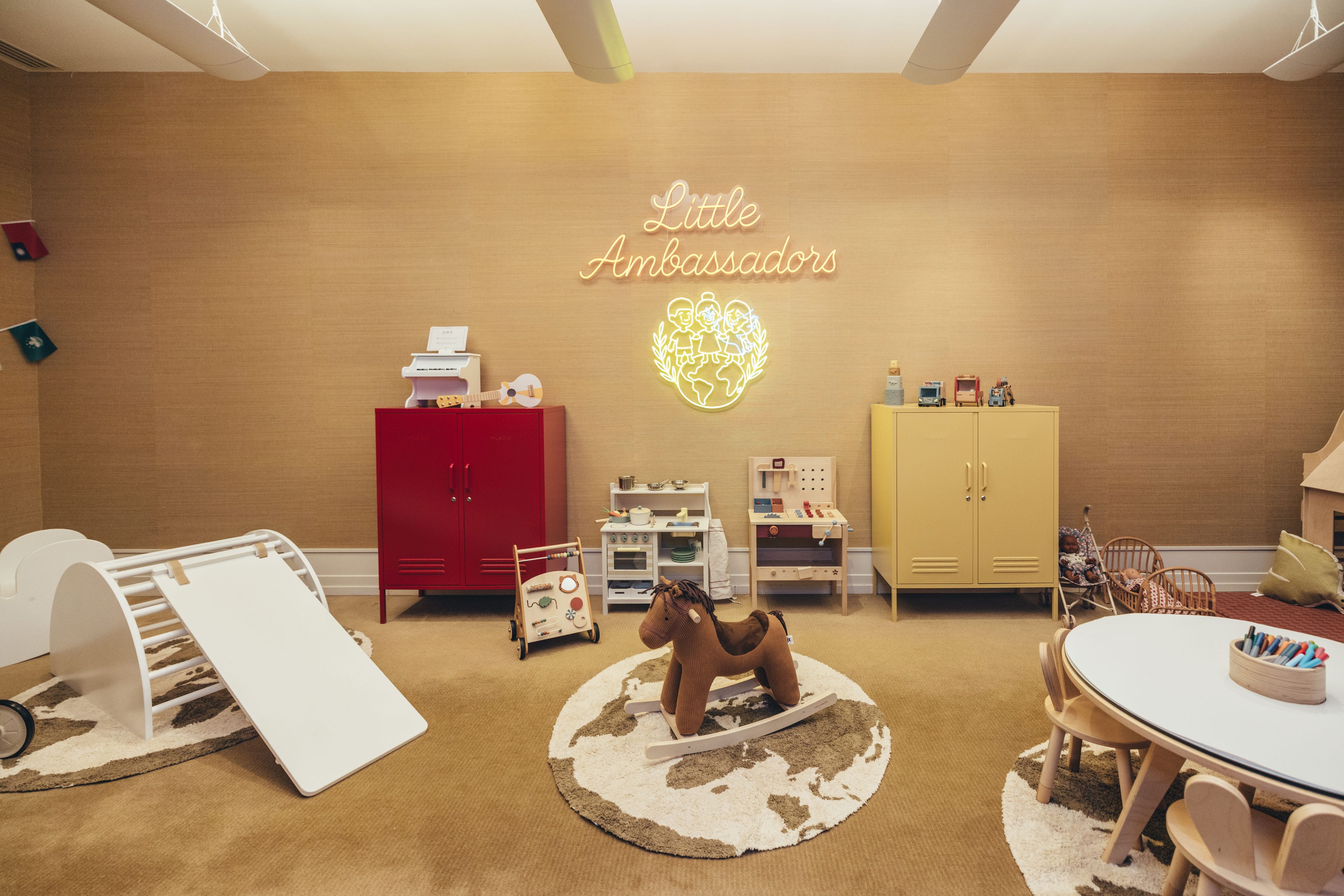 A child's playroom with a red and yellow cabinet, a play kitchen, and a globe on the wall.