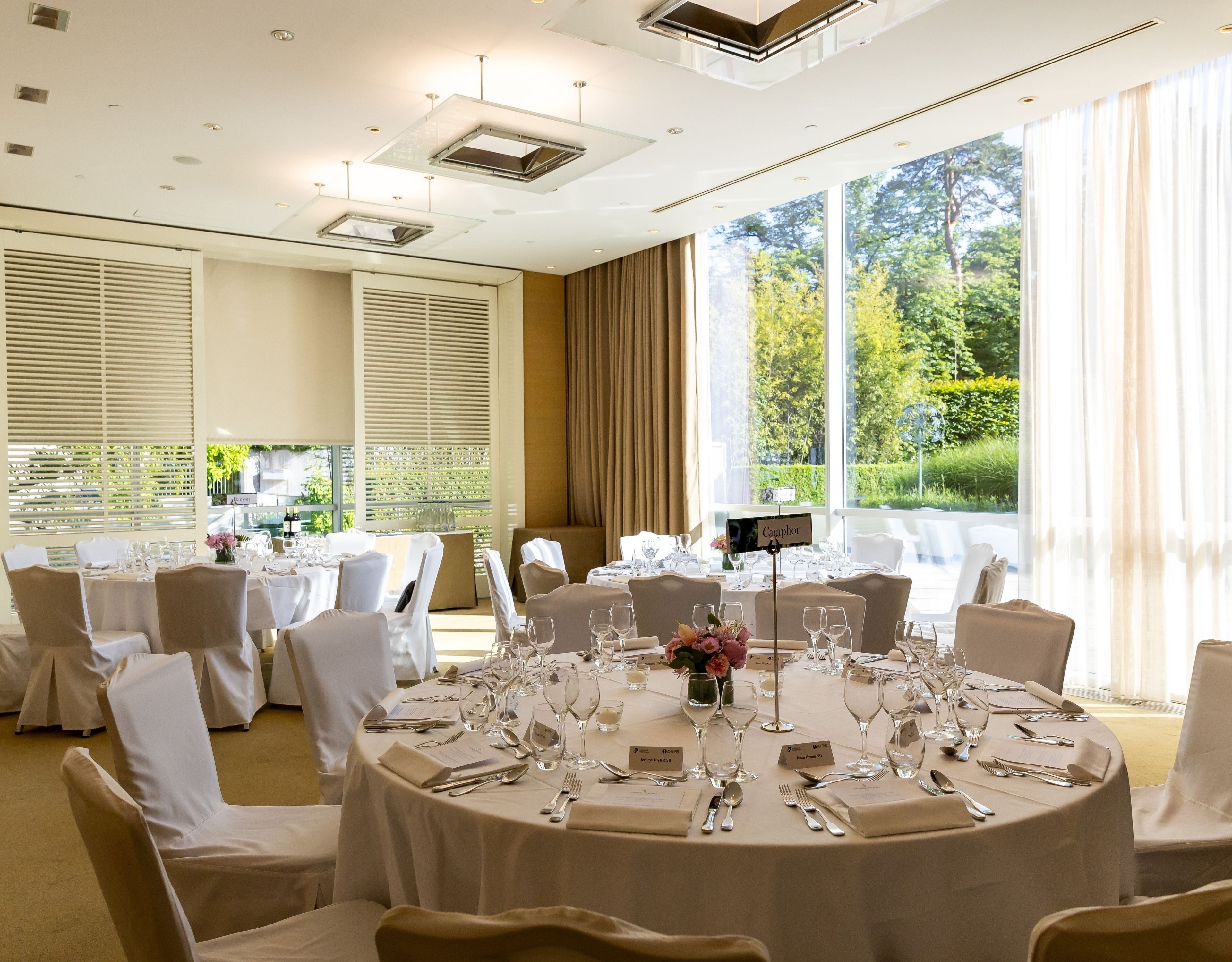 A well-lit conference room with round tables set for a meeting.