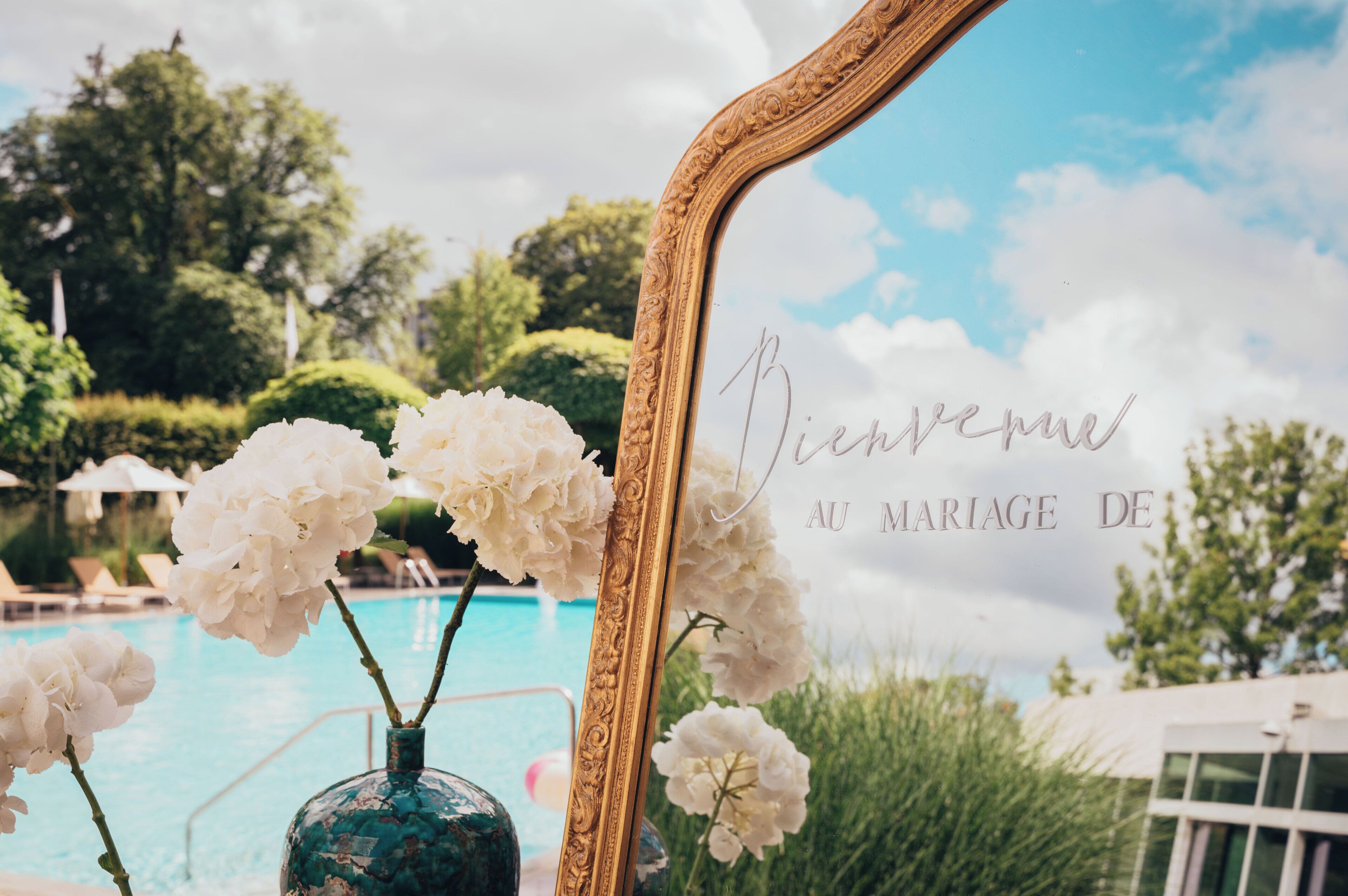 Vista de la piscina con un espejo decorativo y flores blancas.