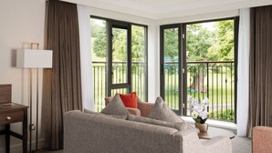 A modern hotel room with a large window, a sofa, a small table, and a lamp. - Roe Valley Resort (Limavady)