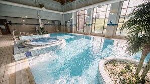 An indoor swimming pool with a hot tub, tiled walls, and a view of the outdoors. - Roe Valley Resort (Limavady)
