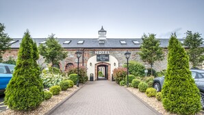 A hotel entrance with a brick facade, a sign reading "HOTEL ROE PARK," and a paved pathway leading to the entrance. - Roe Valley Resort (Limavady)