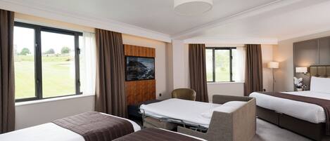 A hotel room with two beds, a desk, a chair, and a large window offering a view of the outdoors.