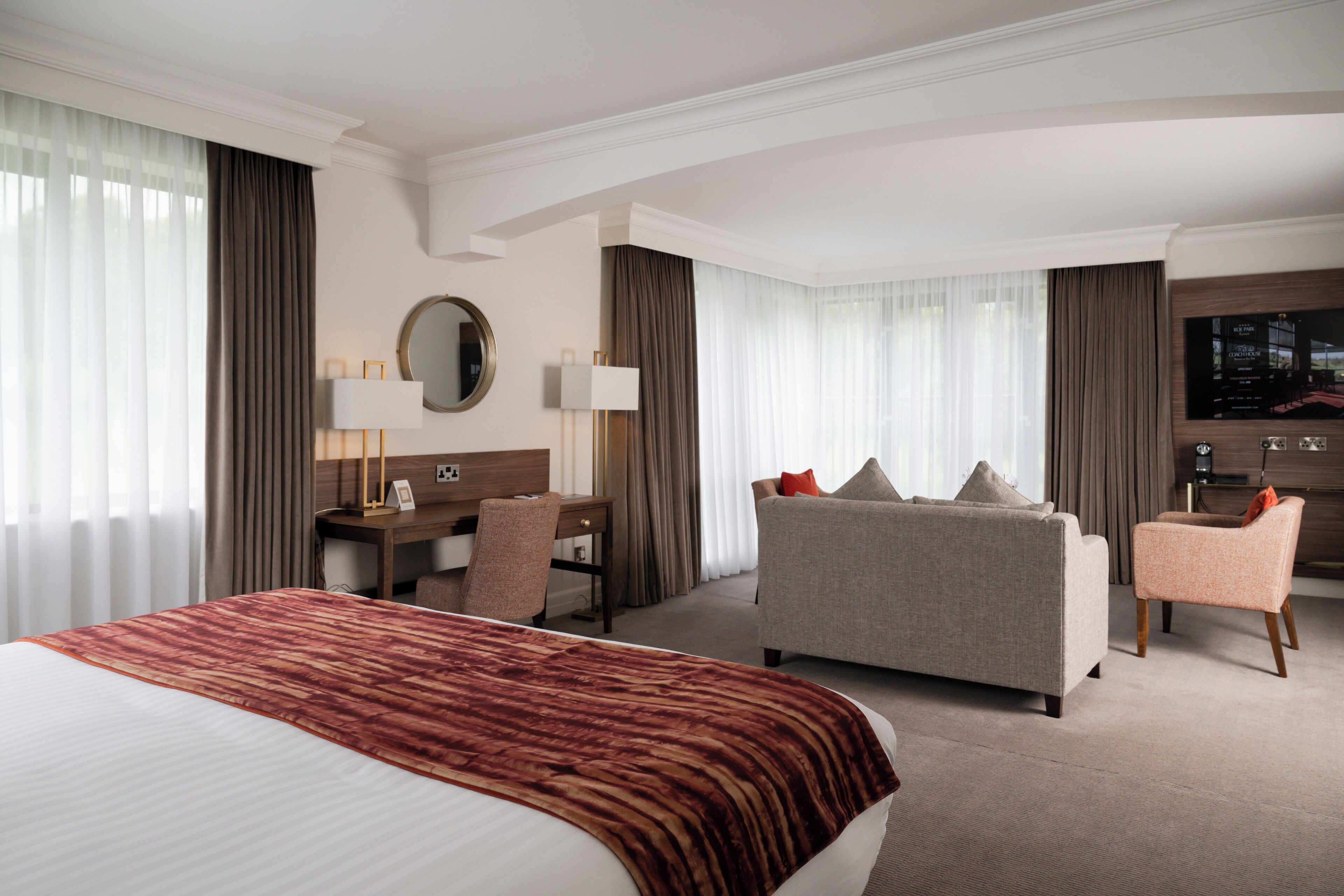 Une chambre d’hôtel avec un grand lit, un canapé, un bureau et une télévision.