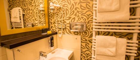 A bathroom with a sink, mirror, towel rack, and patterned wallpaper.