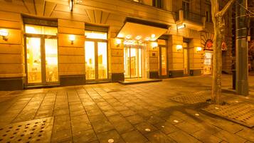 Entrada de hotel con puertas iluminadas y un área de acceso cubierta.