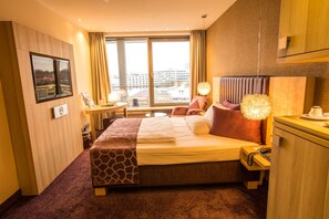 Enjoy a city view from the large bed with a headboard, bedside table, and lamp.