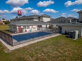 Propiedad residencial con patio trasero cercado, piscina y zona de patio cubierto.