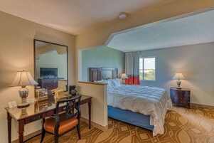 Habitación de hotel con cama, escritorio, silla y un espejo grande.
