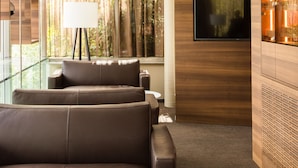 Una sala de estar moderna con un sofá, un televisor y un ventanal con cortinas.
