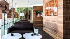 Un vestíbulo moderno con barandilla de cristal, asientos de cuero y mostrador de recepción de madera.