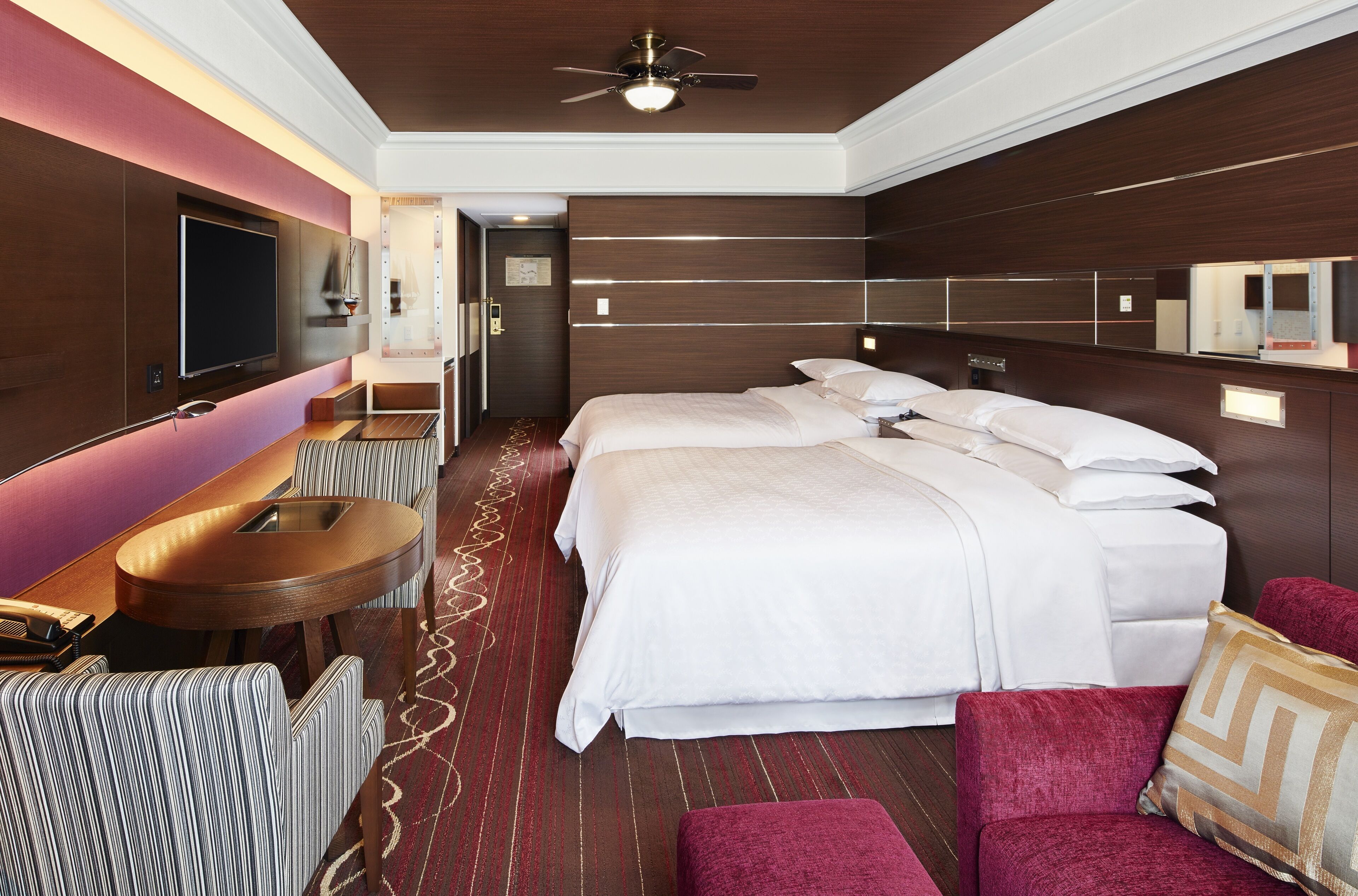 Una habitación de hotel con una cama grande, televisión, escritorio y zona de estar.