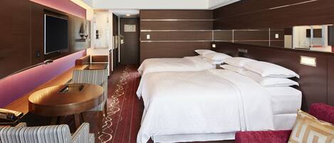 Una habitación de hotel con una cama grande, televisión, escritorio y zona de estar.