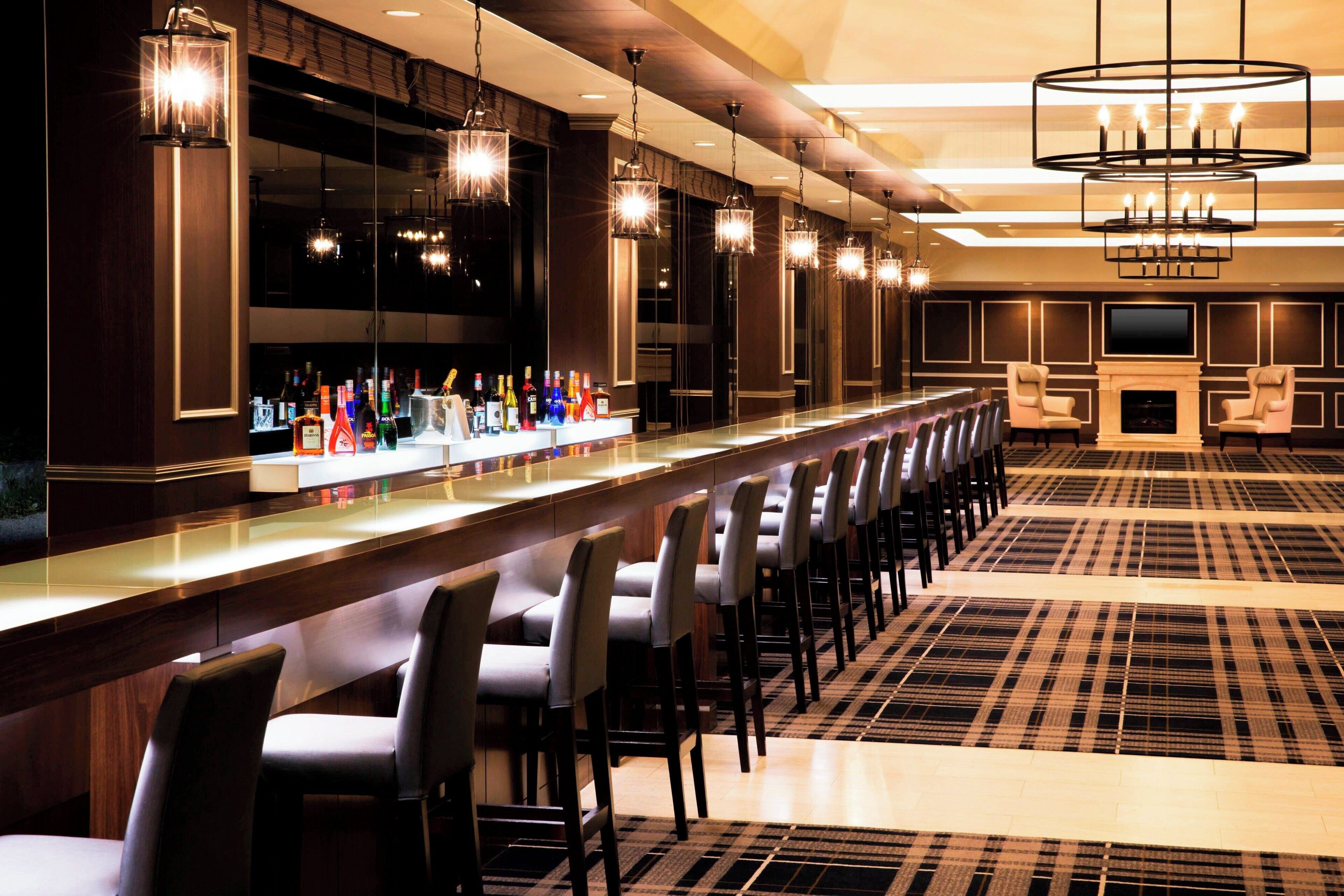 A bar area with multiple seating options and a variety of liquor bottles.