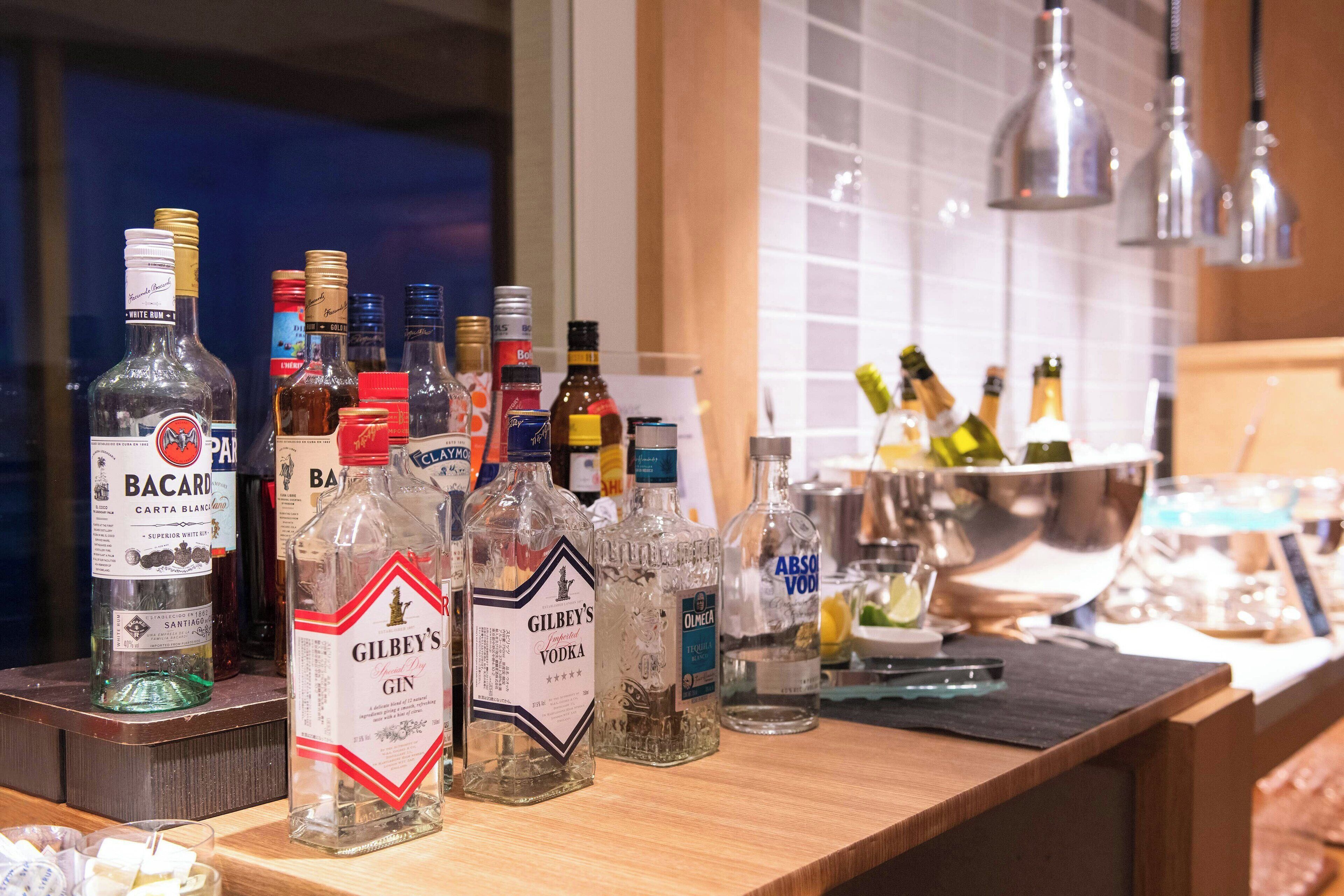 A bar area with various bottles of alcohol, including Bacardi, Gilbey's Gin, and Absolut Vodka.